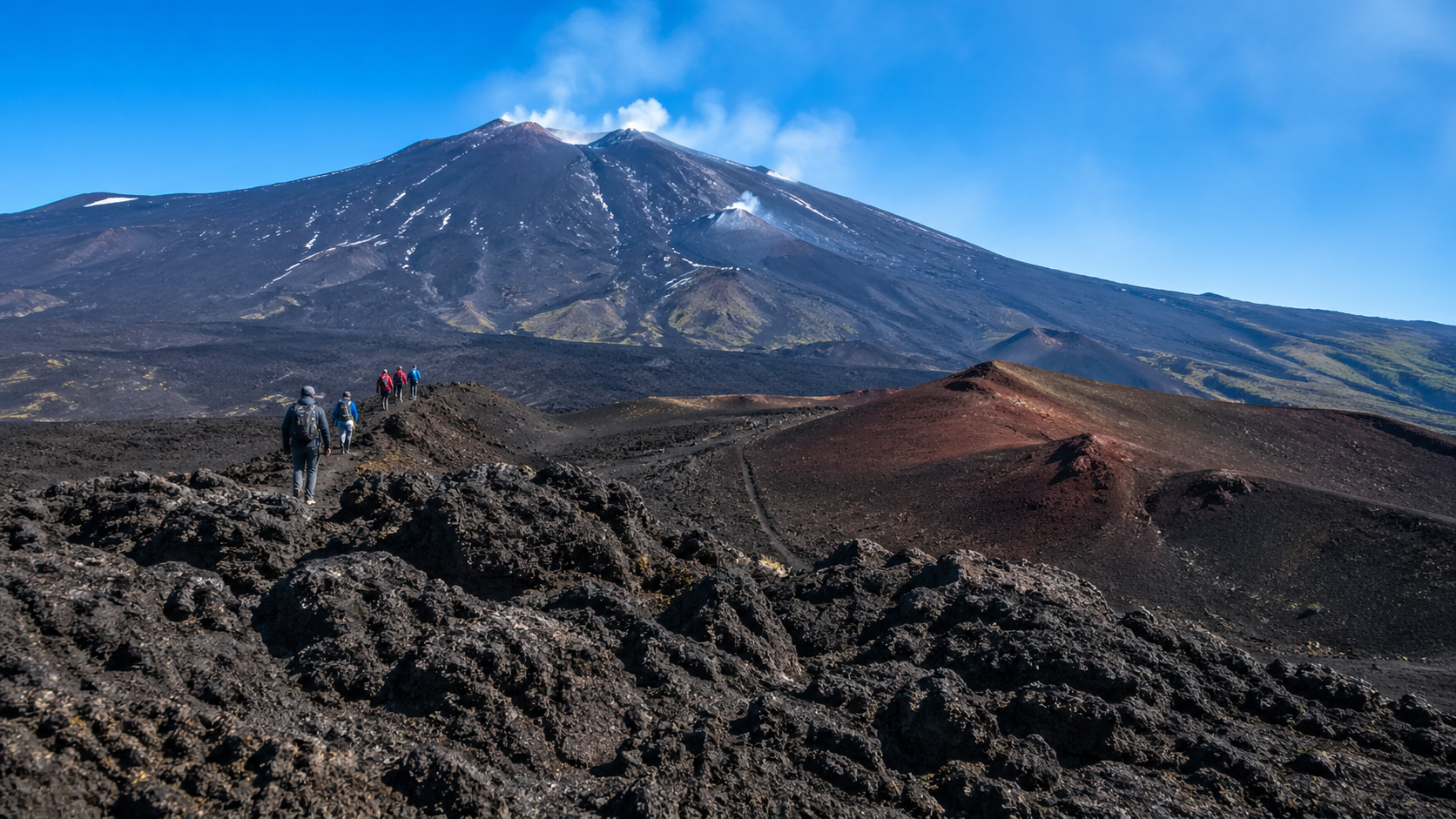 Hikers Traverse Volcanic Terrain Under Clear Sky