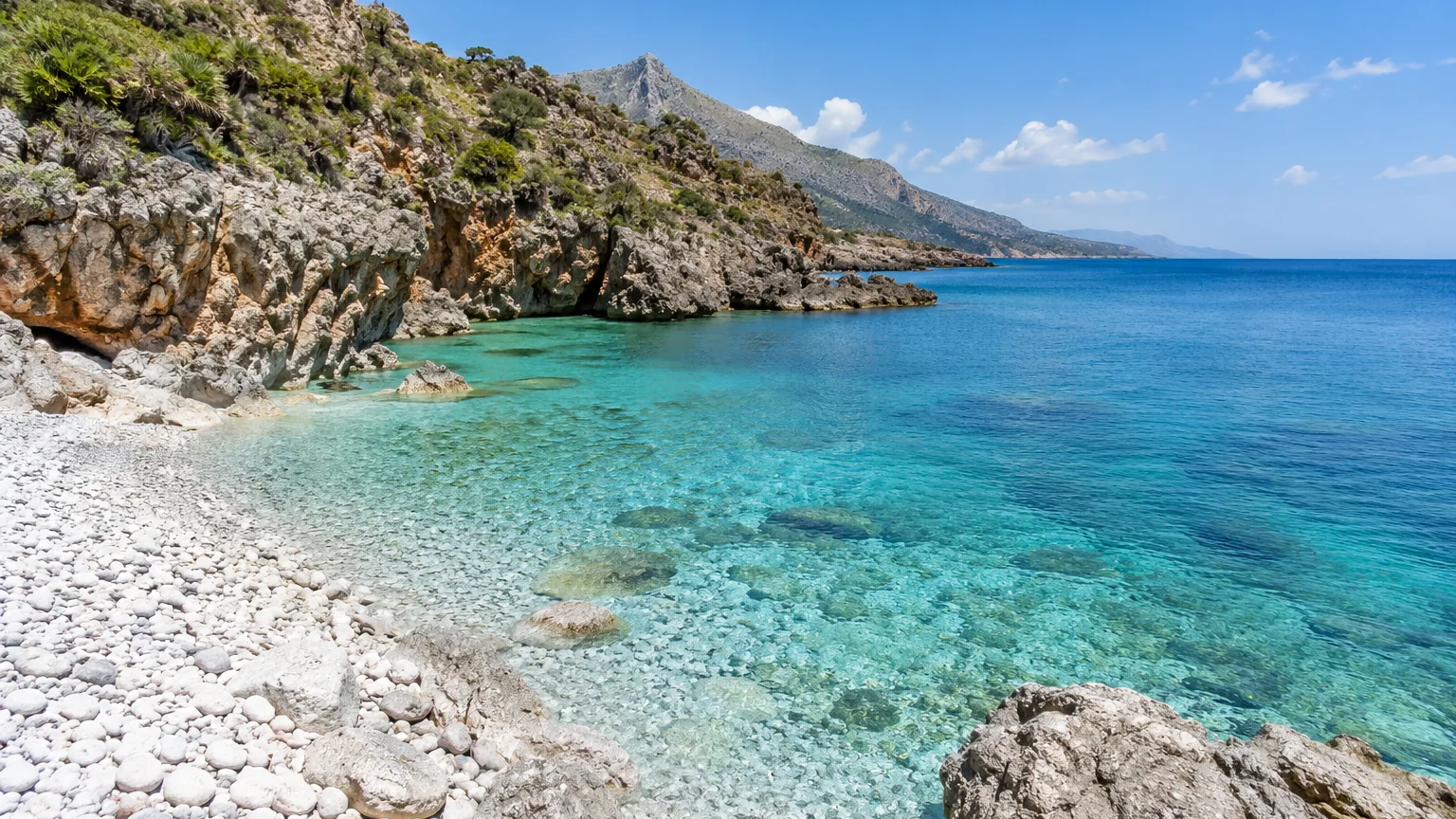 Felsbucht mit türkisem Wasser und weißem Kiesstrand